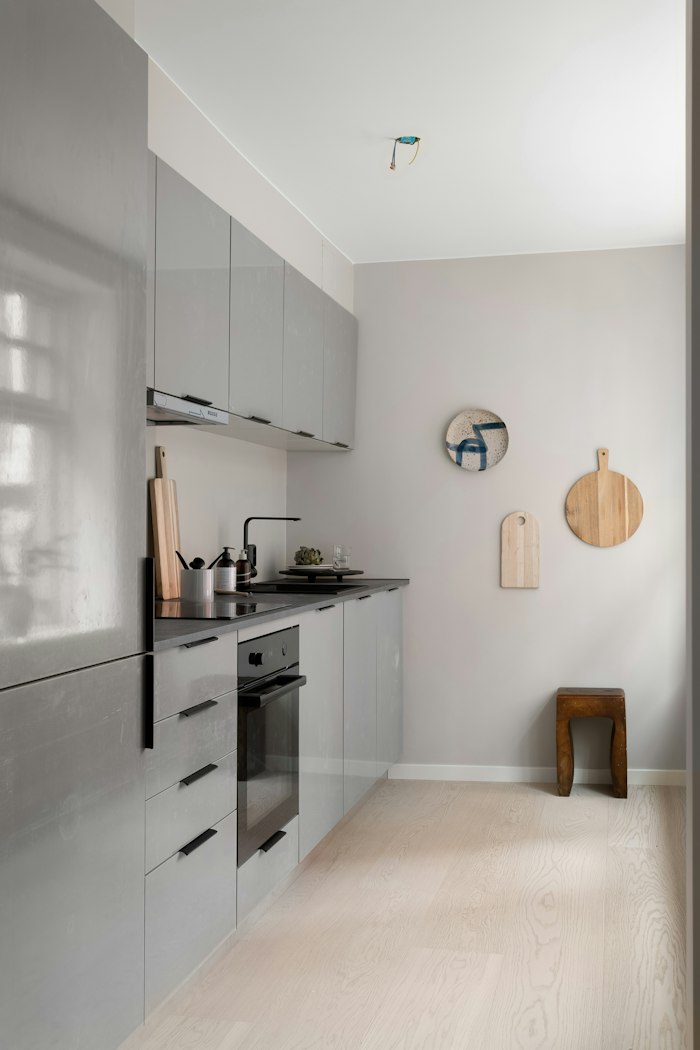 Cocina lineal con muebles grises y suelo de madera clara