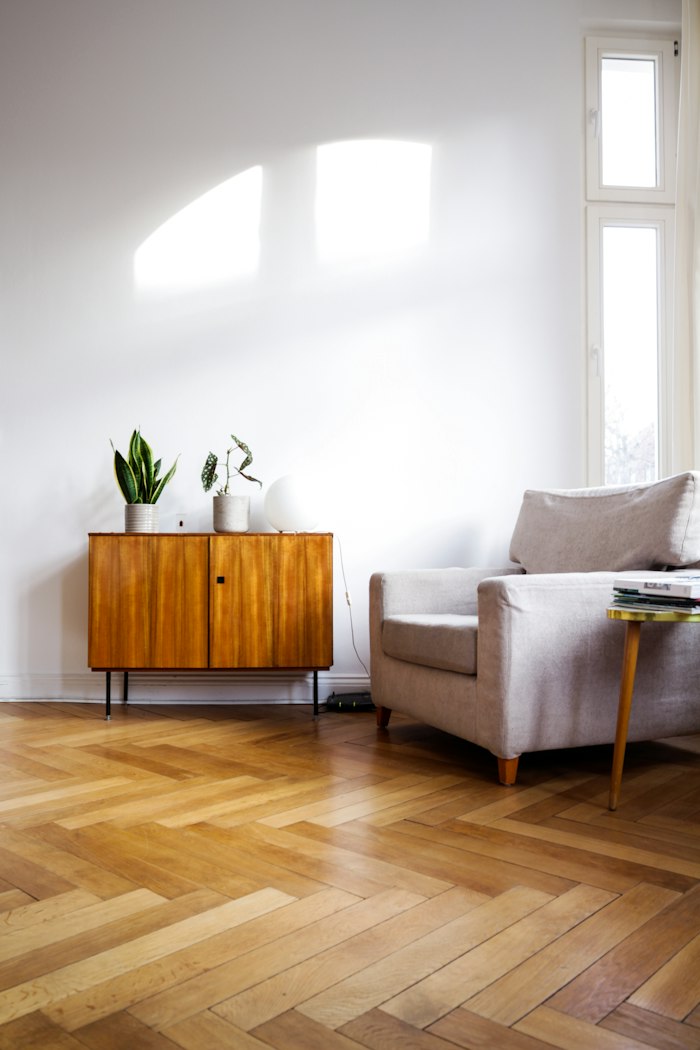 Salón con suelo de madera en espiga, mueble bajo y sillón